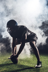 silhouette of athletic american football player in star position against white smoke