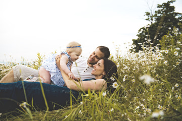 littlegirl and his father and mother enjoying outdoors in field of daisy flowers
