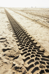 Tracks of tyres of a motorised vehicle on the beach, manmade patterns and structures 