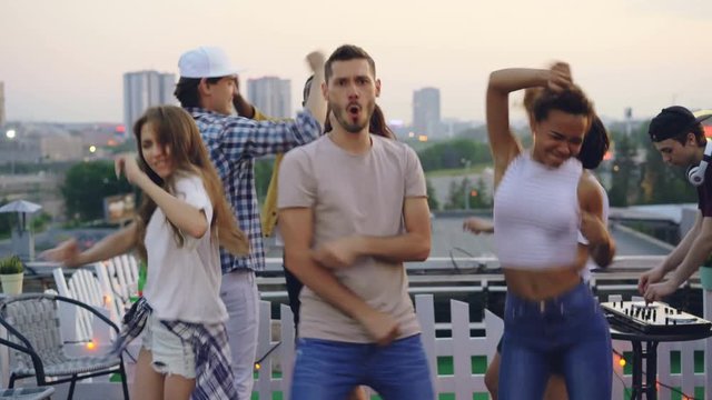 Sudden mood change of group of friends standing with sad faces then enjoying rooftop party, dancing and smiling feeling happiness. Feelings, changing and friendship concept.
