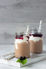 Two bottles of chocolate and banana smoothie with natural yoghurt and black currant. Delicious and healthy breakfast concept. Selective focus. Copy space.