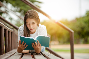 Fototapeta premium Beautiful young brunette woman lying on the amphitheater with a book in her hands. Romantic outdoor conception.