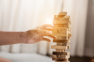 hand  pulling out or placing wood block on the tower.plan and strategy in business. blur for background.