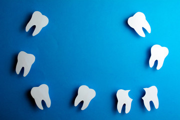 White healthy teeth over blue background  with copy space. Dental care and whitening teeth. Tooth restoration. Installation of the dental implant. Oral dental hygiene Concept.