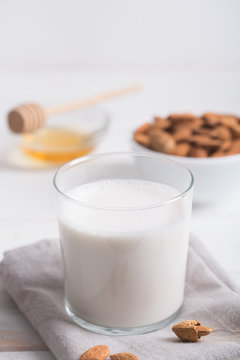 Almond milk and honey on a white wooden table.