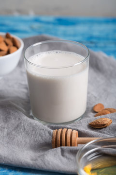 One glass of almond milk on the grey napkin and blue wooden background