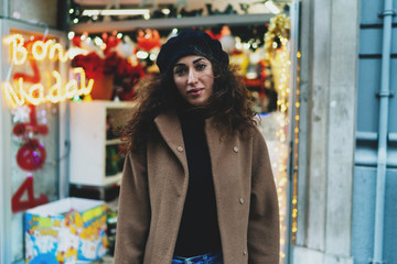 Obraz premium Young successful entrepreneur female standing beside her newly opened shop. Travel blogger walking the new city on autumn time. Hipster girl in stylish outfit walking outdoors during free time.