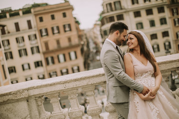 Young newly married couple  posing in Rome with beautiful and ancient architecture in the background