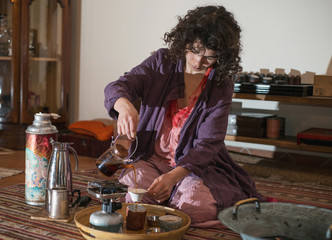 
Asian woman with curly hair prepares tea

