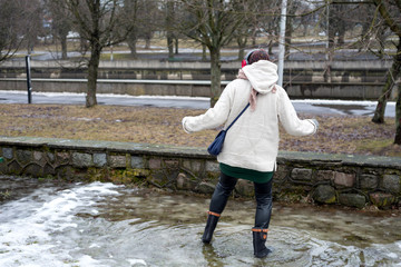 
Woman walks through puddles in rubber boots
