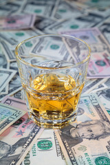 glass of whiskey is on dollar bills of different denominations