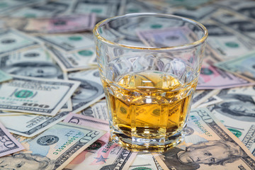 glass of whiskey is on dollar bills of different denominations