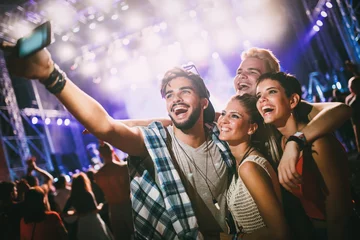 Schilderijen op glas Happy friends taking selfie at music festival © NDABCREATIVITY