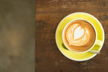 A Cup of hot latte art coffee on wooden table, wooden background