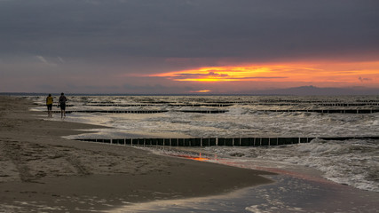 2 Freunde gehen am Strand im Sonnenuntergang spazieren