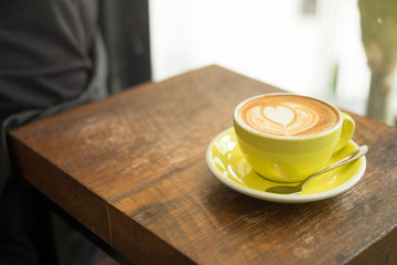 A Cup of hot latte art coffee on wooden table background