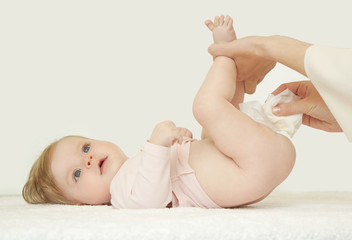 Newborn baby getting a diaper change: mom wiping baby's bottom with baby wipe