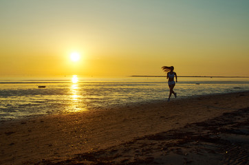 Fototapeta na wymiar girl running by the sea on the beach