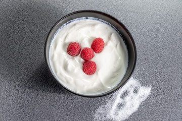 Fresh ripe raspberries on top of a bowl full of curd