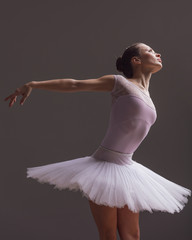 Young beautiful ballerina is posing in studio