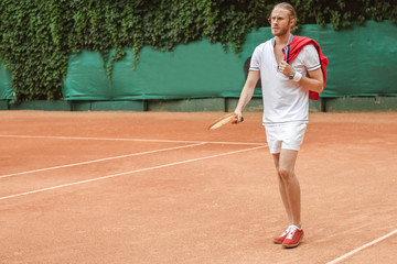 handsome man in sportswear with retro wooden racket on tennis court