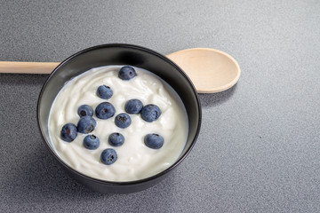 Wooden spoon behind a bowl full of homemade curd with blueberries