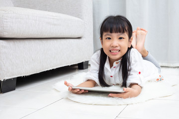 Asian Chinese little girl lying on the floor and playing tablet