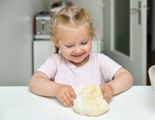 Little girl kneads dough