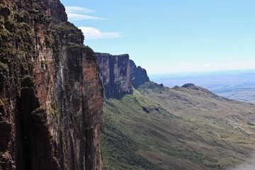Fototapeta premium Strome klify góry Roraima - krajobraz z błękitnym niebem i wodospadem. Widok na Gran Sabana i Mount Roraima. Wenezuela