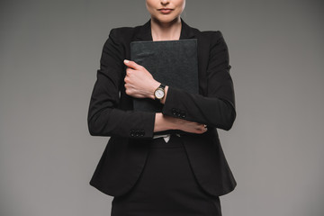 Obraz na płótnie Canvas cropped image of businesswoman holding textbook isolated on grey background
