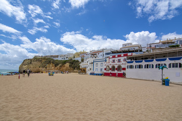 Playa de arena entre acantilados y en frente de la encantadora arquitectura blanca en Carvoeiro, Algarve, Portugal