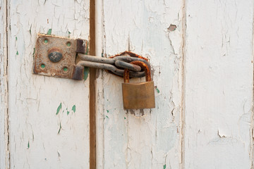 A padlock on a wooden door with peeling paint