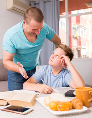 Obraz premium Man with his adult son are reading book together for homework