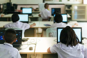 Primary Students study by computer in classroom.