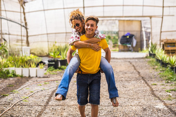 young beautiful teenager play with his mother middle age pretty woman carrying her to his back. couple mother son having fun together like a perfect family in outdoor leisure activity. happy people