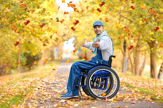 Rollstuhlfahrer im Park im Herbst - bunte Blätter fallen