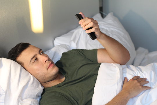 Handsome man looking at phone in bed