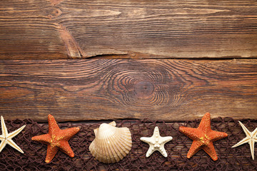 Brown fishing net, starfish and shell on wooden wall background