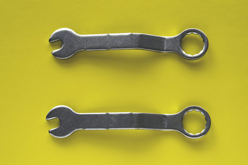 Dwa metalowe klucze do śrub wyizolowane na żółtym tle