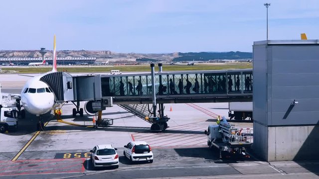 Airport passengers boarding on a plane, people walking through jet bridge. People walking in airport