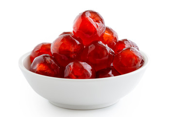Red glace cherries in white bowl isolated on white.