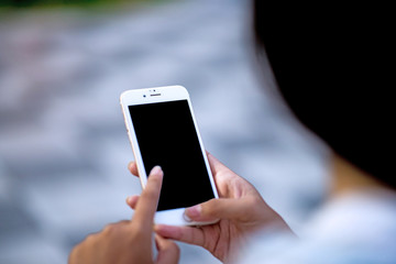 Mockup image of a woman holding and displaying a white mobile phone with a black screen with a blank screen on a table in a modern cafe. Ideas for working with communication tools.