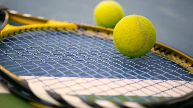 Close up of tennis equipment on the court. Sport, recreation concept. Yellow racket with a tennis ball in motion on a clay green blue court next to the white line with copy space and soft focus.