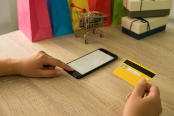 Woman holding credit card and using smartphone for shopping online.