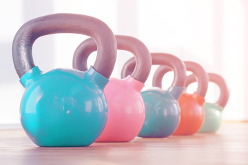 Fototapeta na wymiar Colorful kettlebells in a row in a gym. Toning.