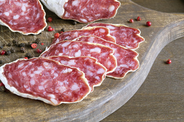 Obraz premium slices of French cheese-dried salami with spices on wooden background