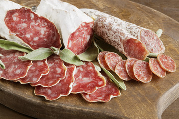 slices of French cheese-dried salami with spices on wooden background