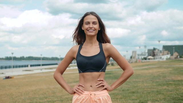 Mid section portrait happy smiling of fit woman's torso with her hands on hips. Female runner outdoors slim skinny belly stomatch muscles abdominal.