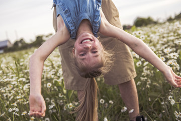 Portrait of Happy little blond girl playing upside down
