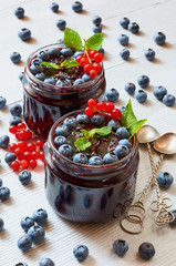 Blueberry smoothies in the glasses with fresh mint, red currant and vintage spoons on the gray background close up. Summer detox superfoods breakfast or cold healthy dessert. Side view